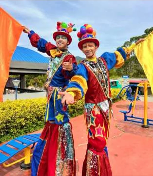 Dos zanqueros con trajes brillantes y sombreros de pompones